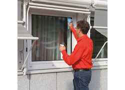 Mann in einem rotem Hemd der die Fenster putzt