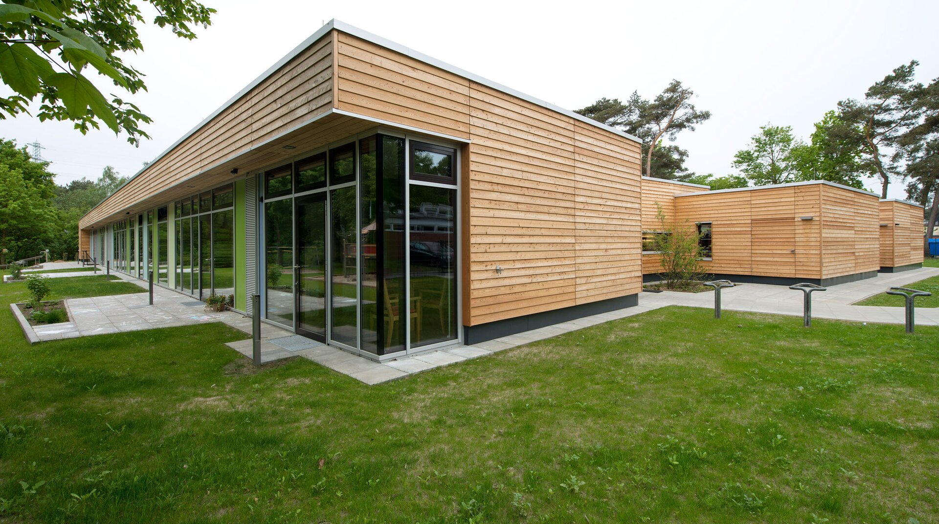 Kindergarten Geesthacht, Blick auf Eckansicht der Außenfassade, Haus verkleidet mit horizontalen Holzpanelen, Garten