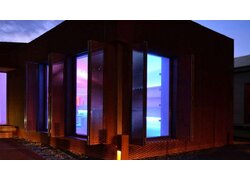 Passivhaus Eco Architekturbüro, bei Nacht, blau beleuchtet im Inneren, Ansicht von außen
