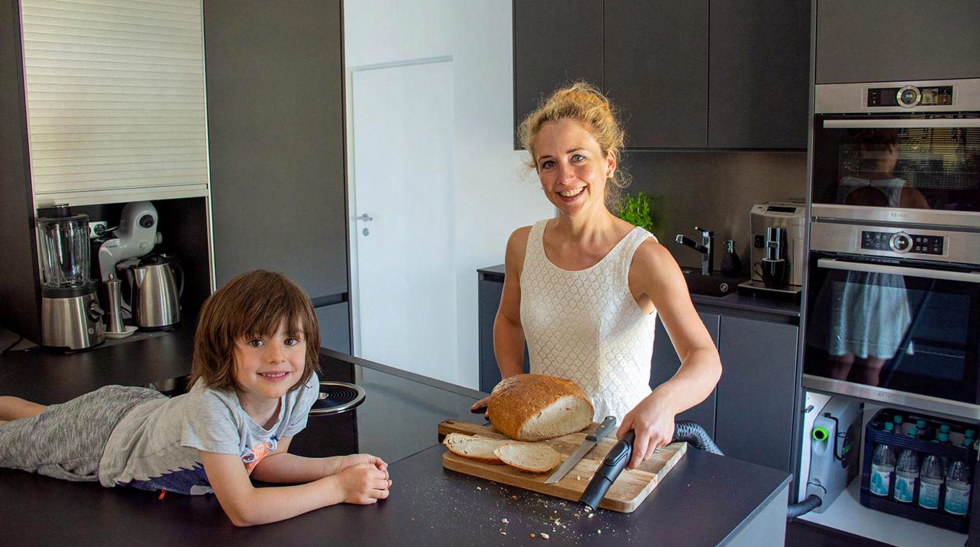 Mutter und Kind in Küche saugen Brotkrümel ein