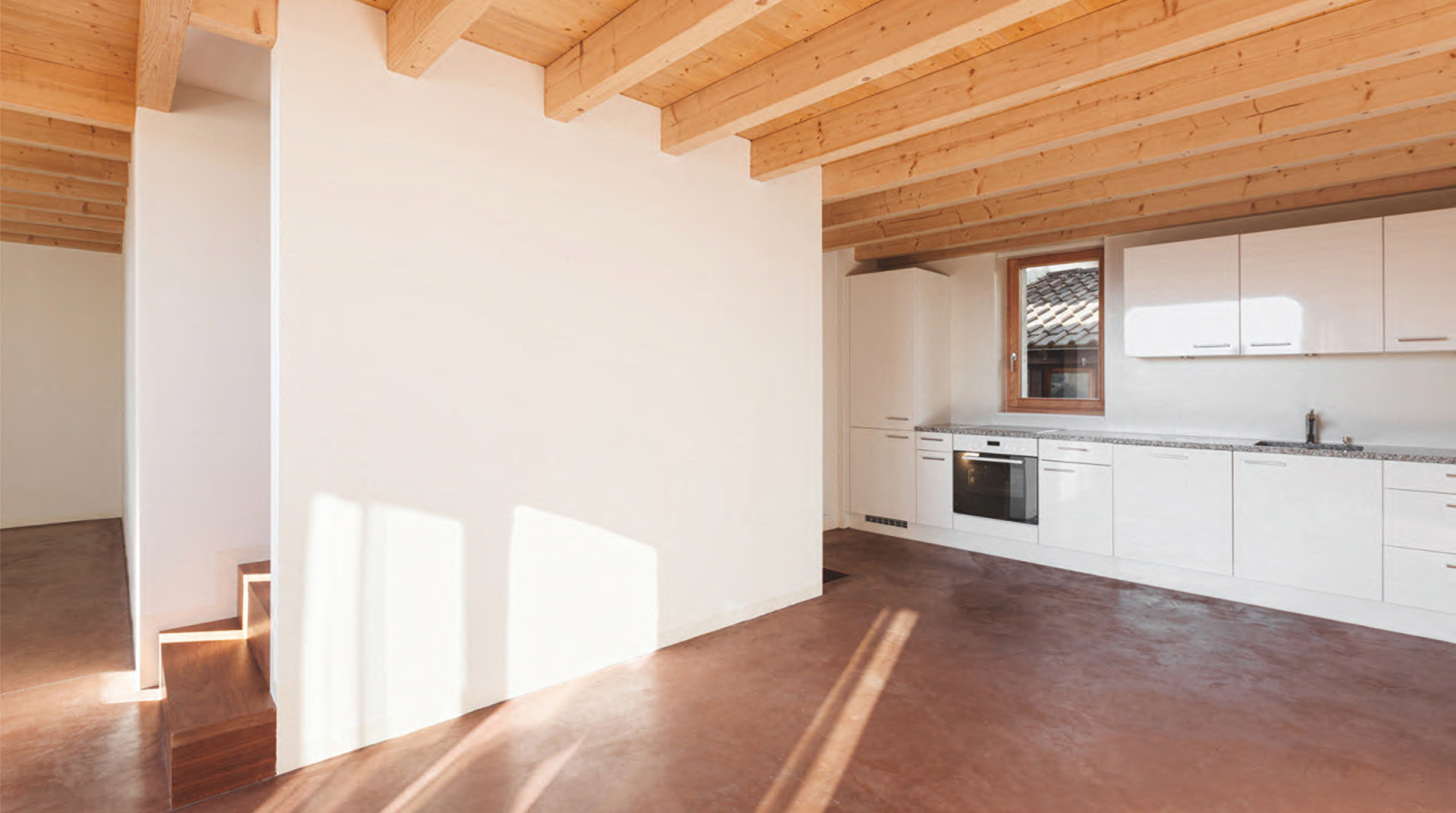 Eine helle Loft von innen mit Ansicht auf Küche und Treppe
