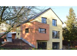 Müllers Bau Einfamilienhaus Konz Könen, Sicht auf Außenfassade, gelbes orange farbenes Haus, Blick durch blätterlose Bäume