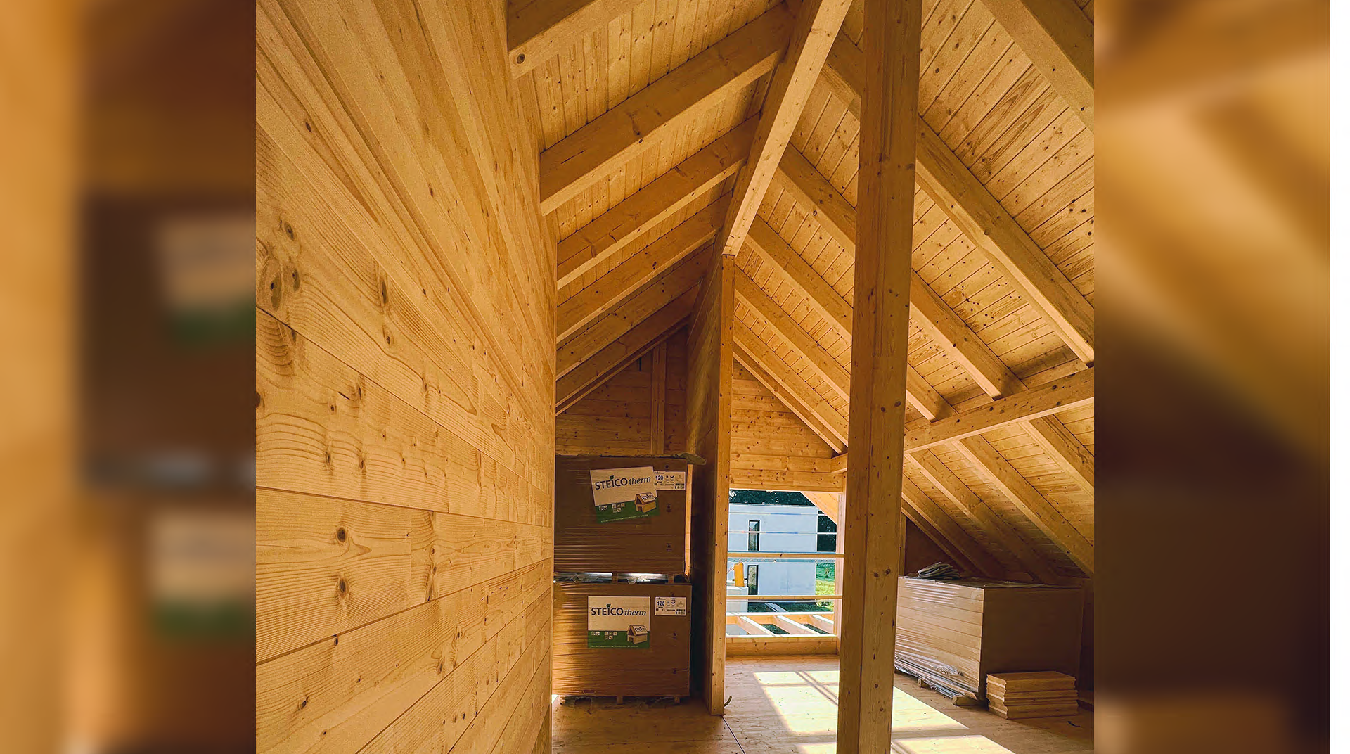Holzdachboden eines MaWood Hauses mit Balken, Fenster und Kartons 